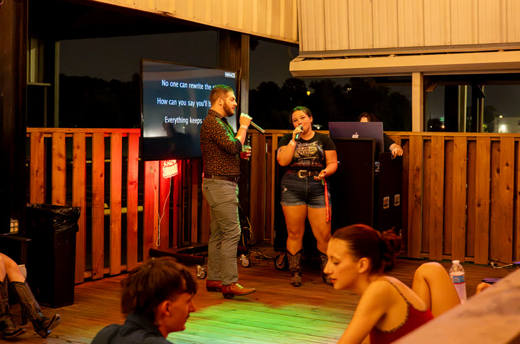 Person singing karaoke while friends cheer